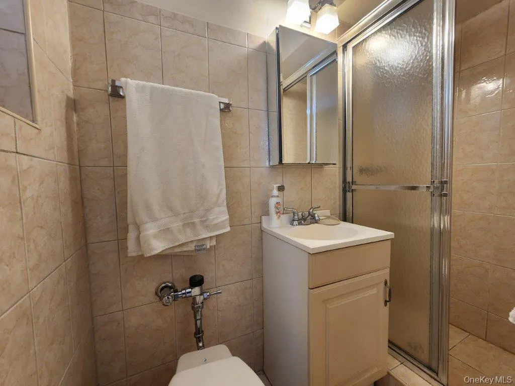 Full bath featuring a shower stall, vanity, and tile walls Full bath featuring a shower stall, vanity, and tile walls