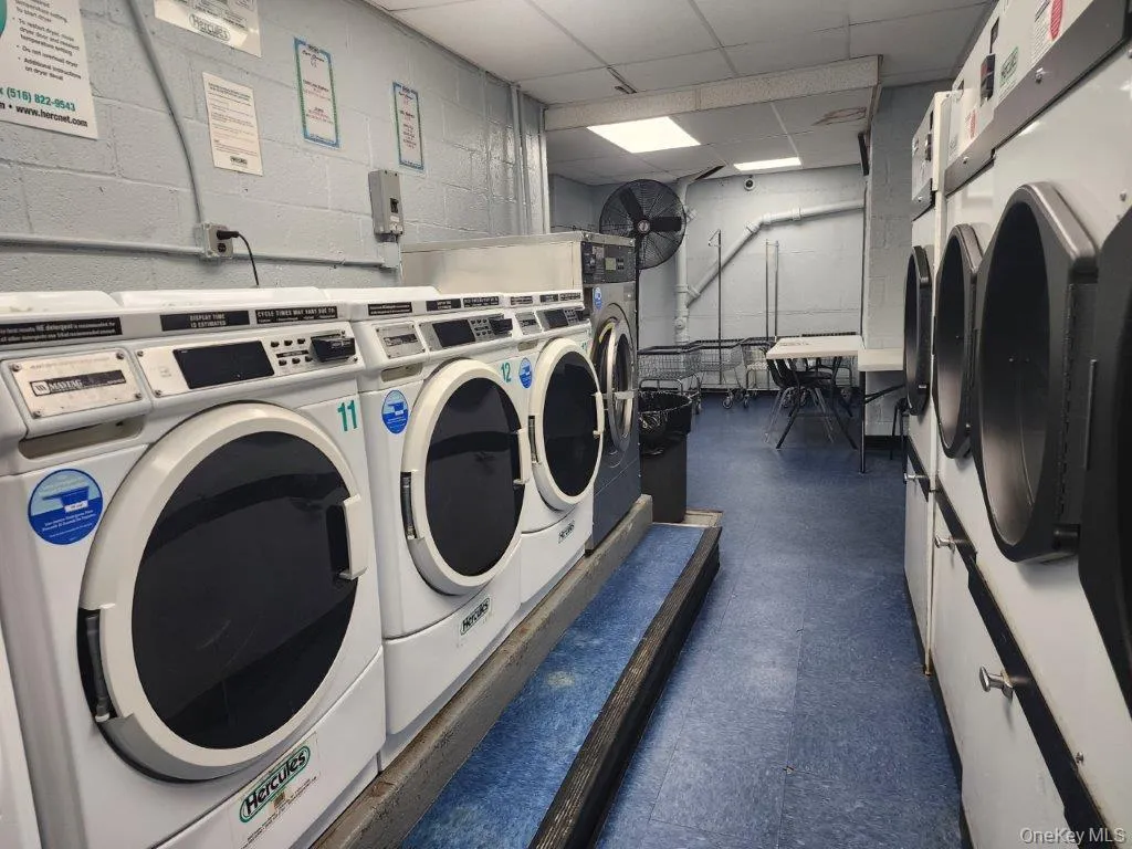 Communal laundry room with washer and clothes dryer and concrete block wall Communal laundry room with washer and clothes dryer and concrete block wall