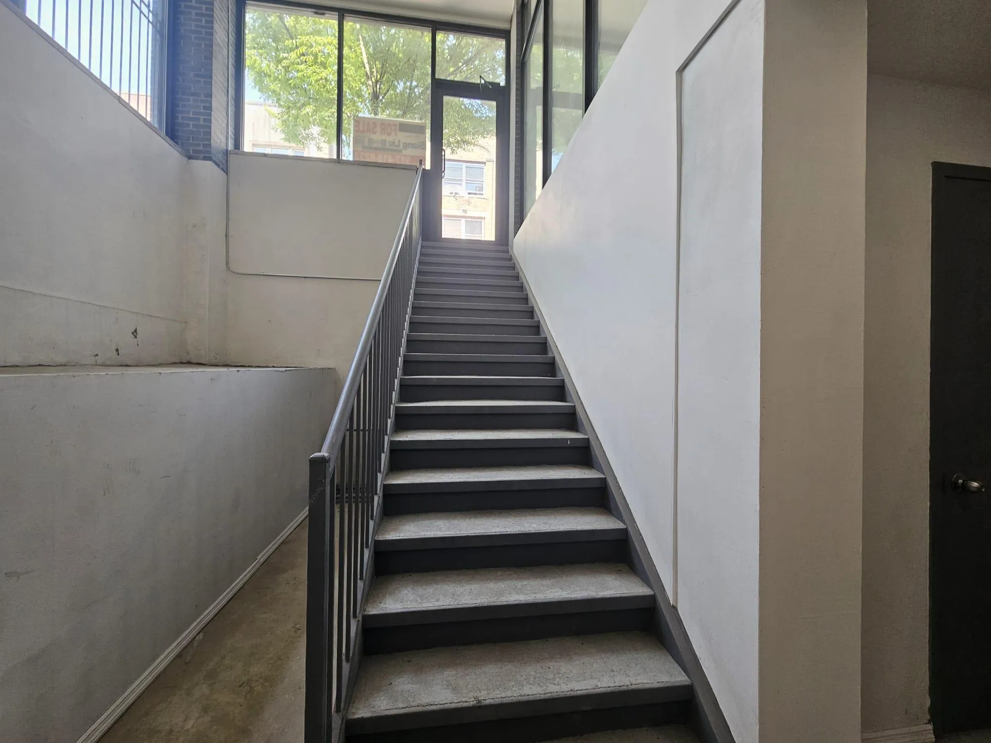 Staircase featuring healthy amount of natural light and concrete flooring Staircase featuring healthy amount of natural light and concrete flooring