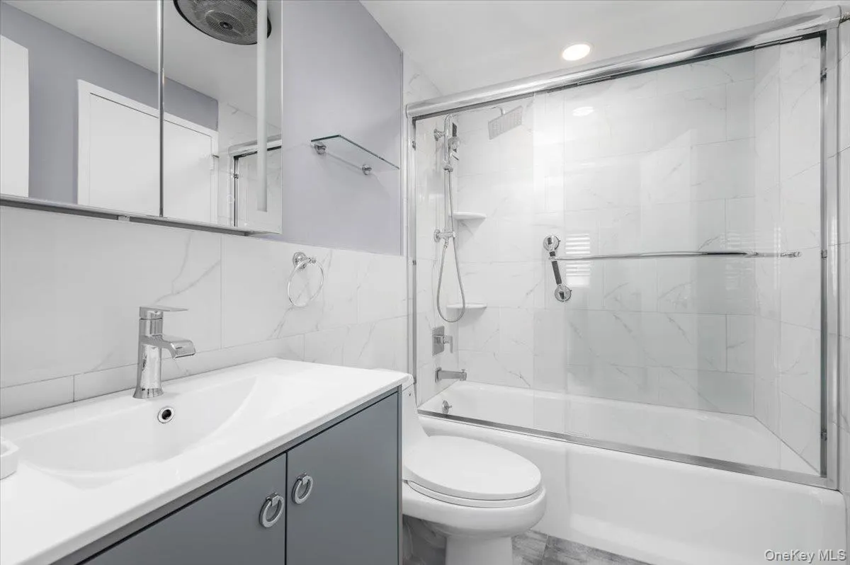 Renovated Full bath featuring vanity, shower / bath combination with glass door, tile walls, and recessed lighting Renovated Full bath featuring vanity, shower / bath combination with glass door, tile walls, and recessed lighting