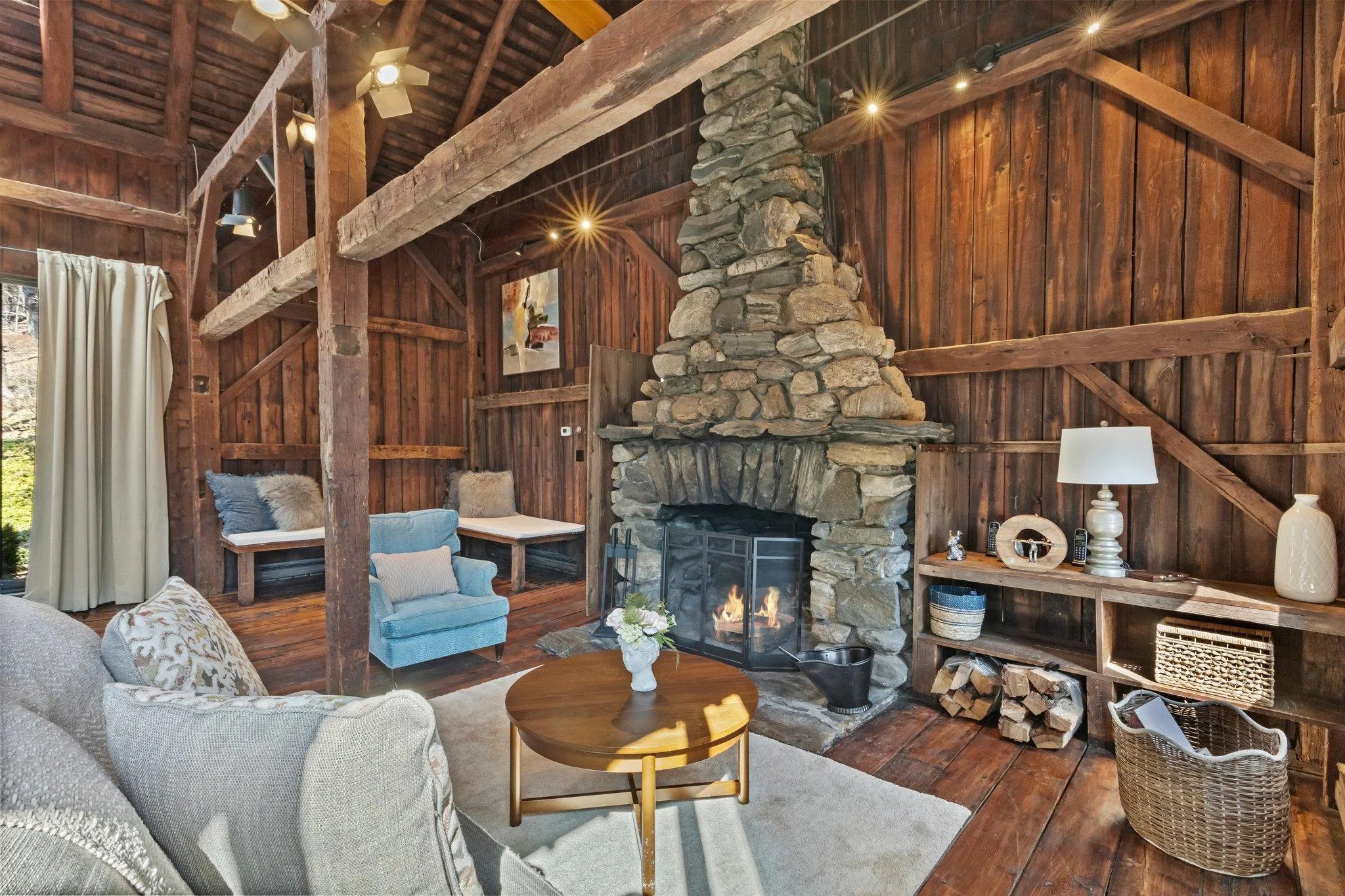 Living room with hardwood / wood-style flooring, wooden ceiling, wood walls, and a stone fireplace Living room with hardwood / wood-style flooring, wooden ceiling, wood walls, and a stone fireplace
