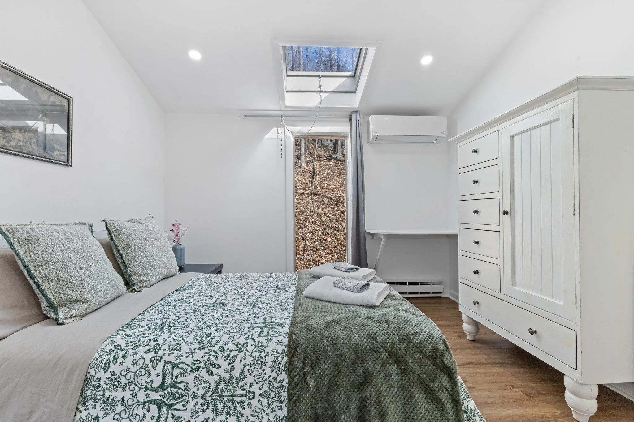 Bedroom featuring an AC wall unit, a skylight, baseboard heating, wood finished floors, and recessed lighting Bedroom featuring an AC wall unit, a skylight, baseboard heating, wood finished floors, and recessed lighting