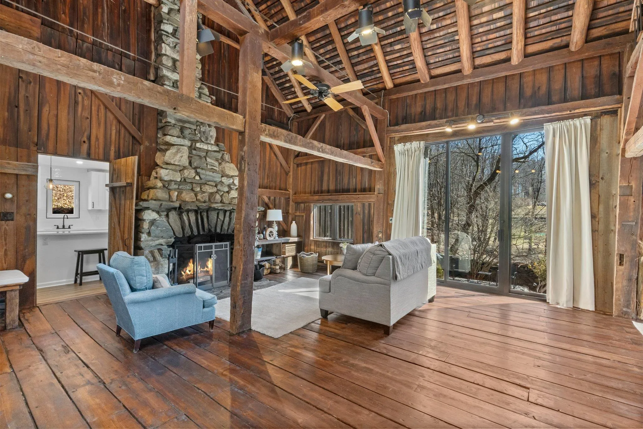 Living area featuring hardwood / wood-style floors, wooden walls, a wooden ceiling with exposed beams, high vaulted ceiling, and plenty of natural light Living area featuring hardwood / wood-style floors, wooden walls, a wooden ceiling with exposed beams, high vaulted ceiling, and plenty of natural light