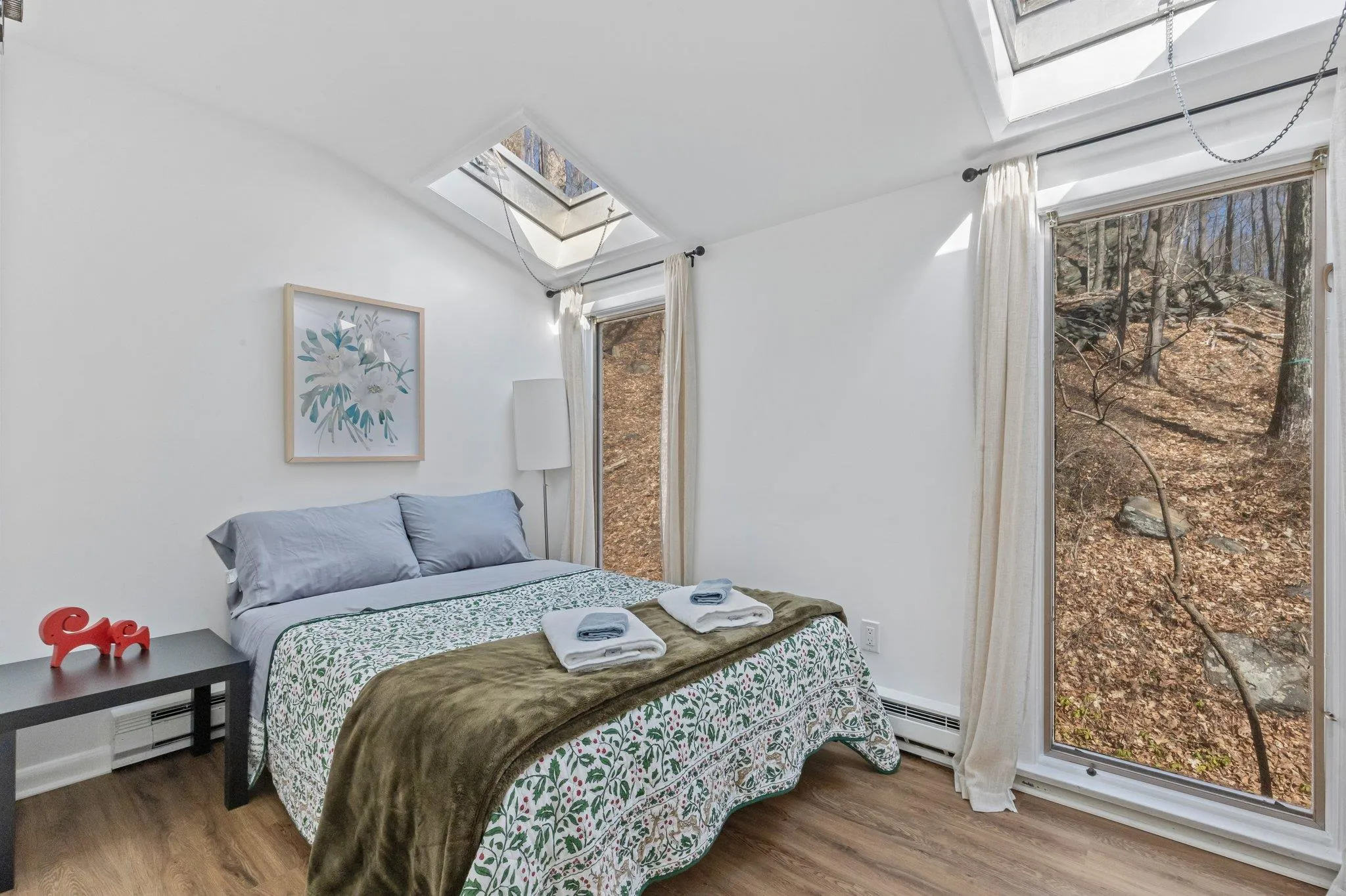 Bedroom featuring a skylight, wood finished floors, baseboard heating, lofted ceiling, and a baseboard heating unit Bedroom featuring a skylight, wood finished floors, baseboard heating, lofted ceiling, and a baseboard heating unit