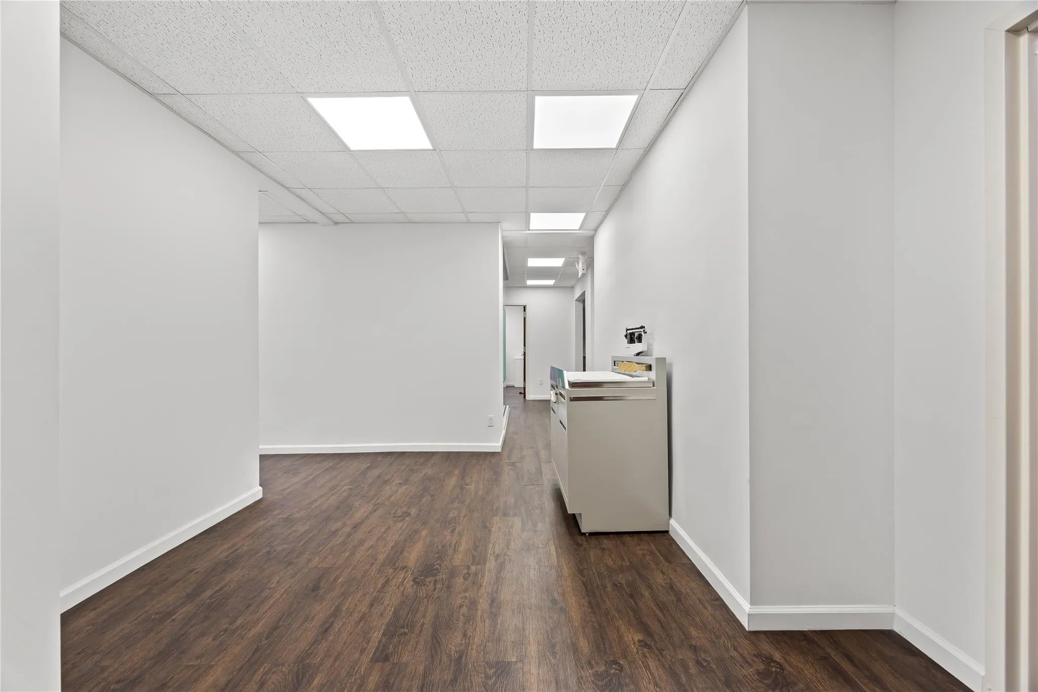 Empty room featuring dark wood-style flooring and a paneled ceiling Empty room featuring dark wood-style flooring and a paneled ceiling