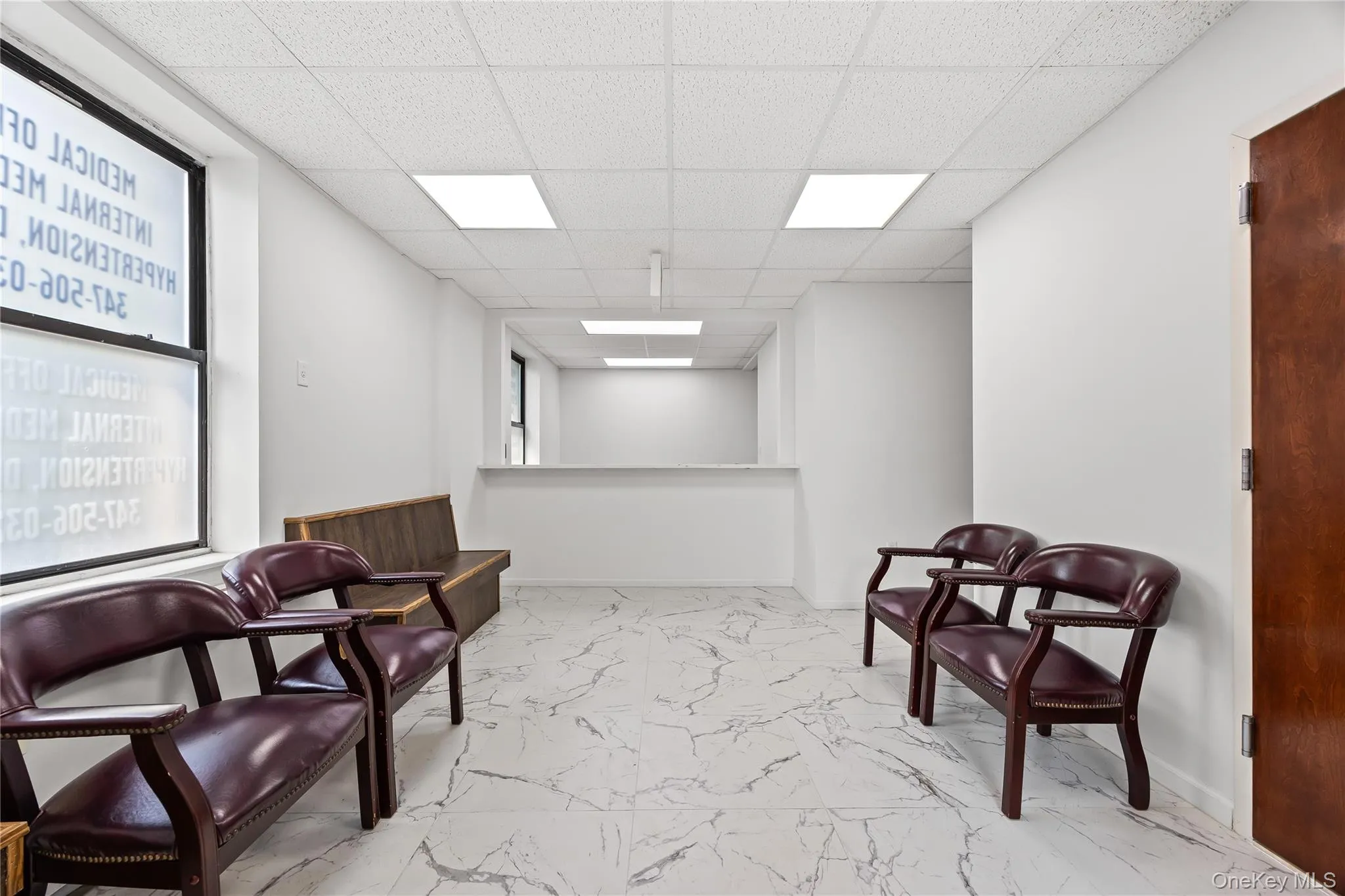 Living area featuring marble finish floors and a drop ceiling Living area featuring marble finish floors and a drop ceiling