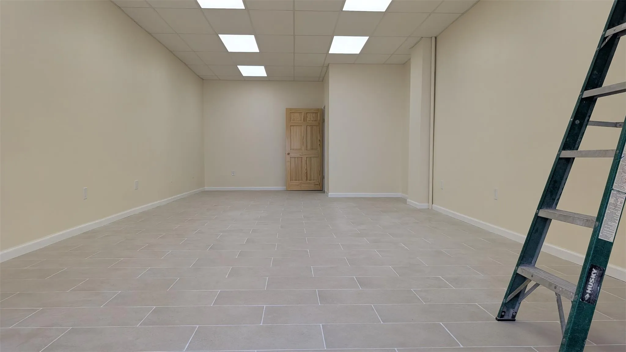 Empty room with a drop ceiling and baseboards Empty room with a drop ceiling and baseboards
