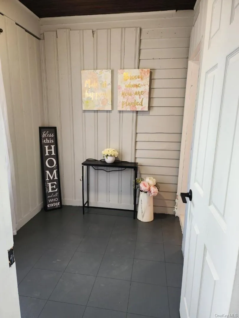 Unfurnished room featuring dark tile patterned flooring and wooden walls Unfurnished room featuring dark tile patterned flooring and wooden walls