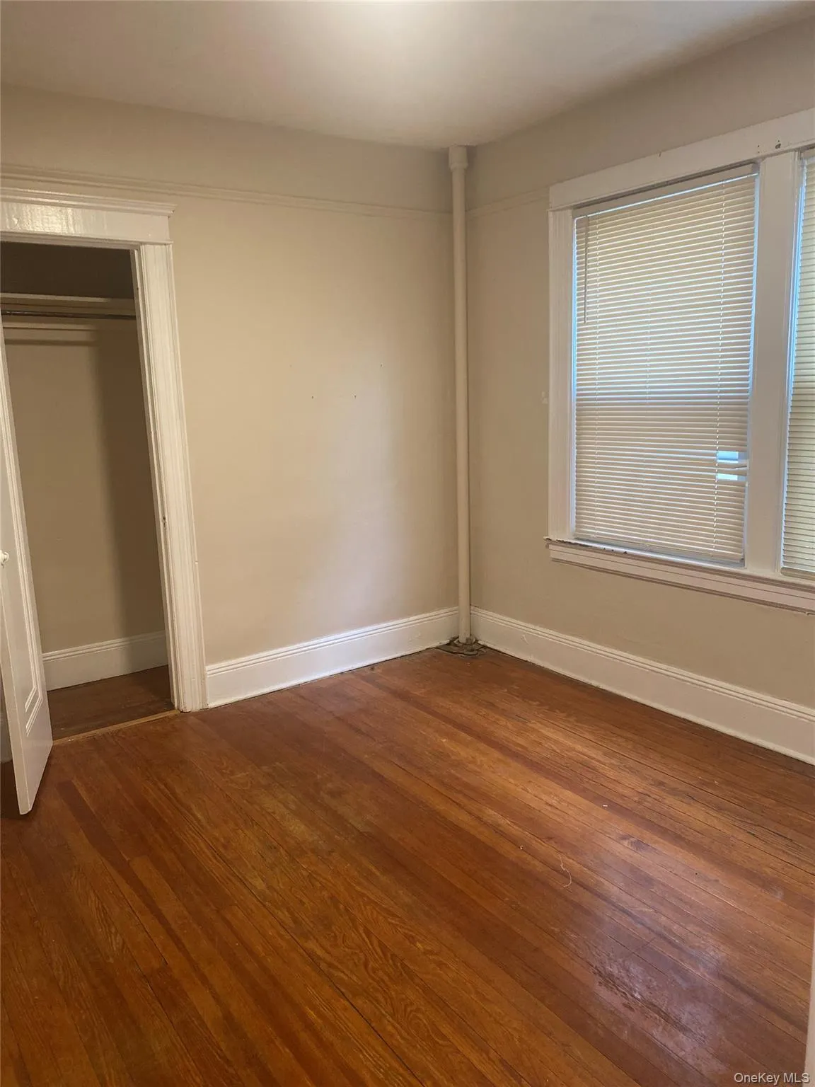 Unfurnished bedroom with dark wood finished floors and a closet Unfurnished bedroom with dark wood finished floors and a closet