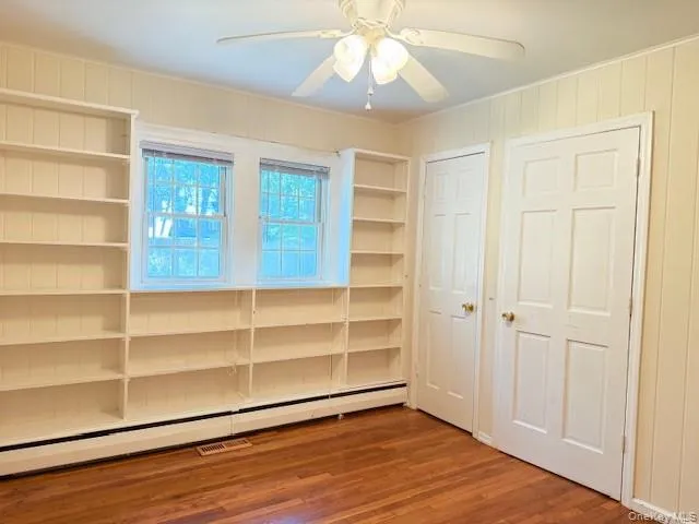 Unfurnished bedroom with a baseboard radiator, wood finished floors, and a ceiling fan Unfurnished bedroom with a baseboard radiator, wood finished floors, and a ceiling fan