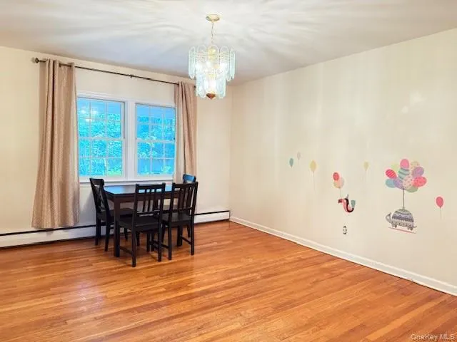 Dining space with light wood-type flooring, a chandelier, a baseboard radiator, and baseboard heating Dining space with light wood-type flooring, a chandelier, a baseboard radiator, and baseboard heating