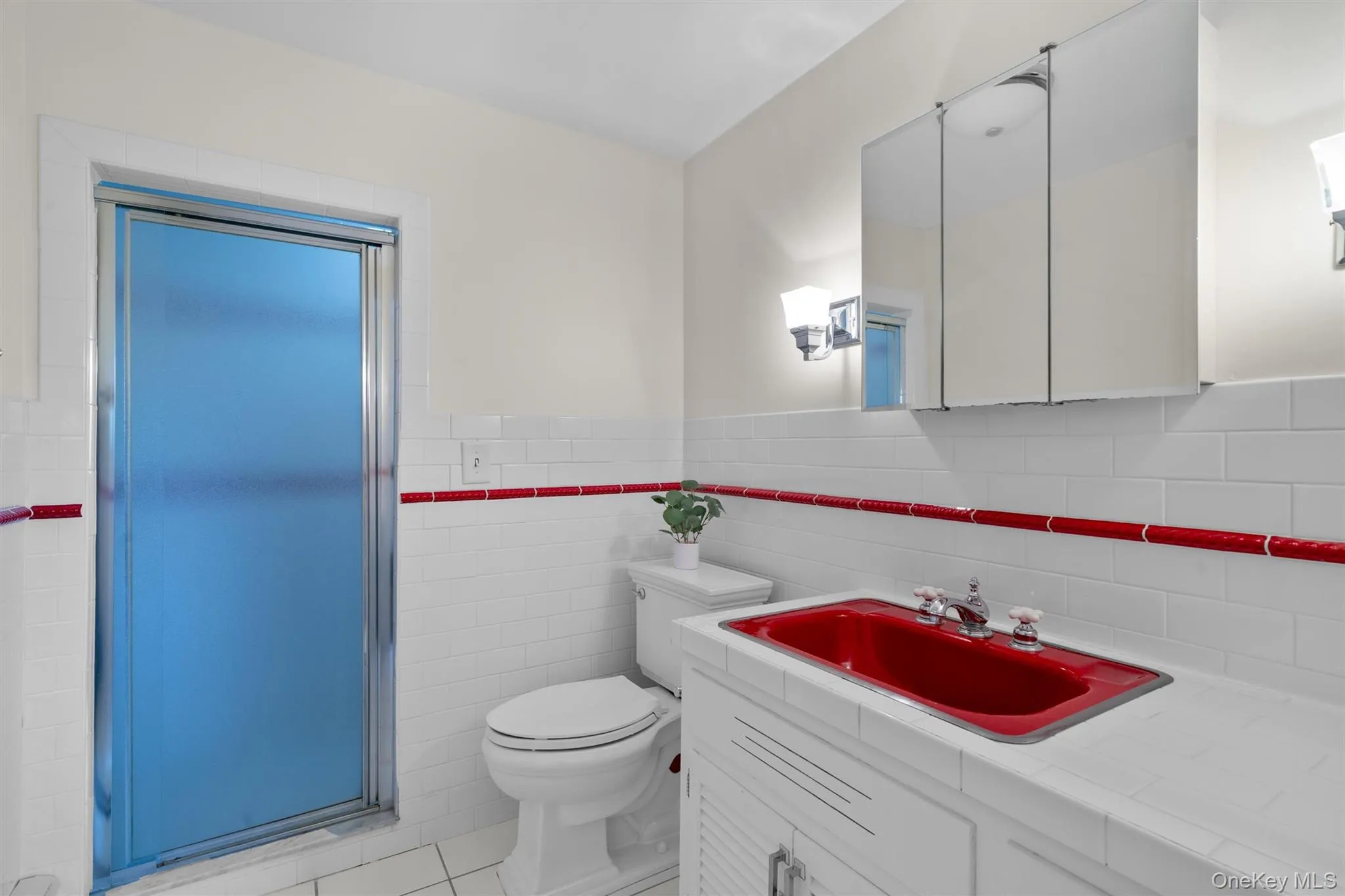 Bathroom with vanity, tile patterned flooring, and a shower with glass door. Bathroom with vanity, tile patterned flooring, and a shower with glass door.
