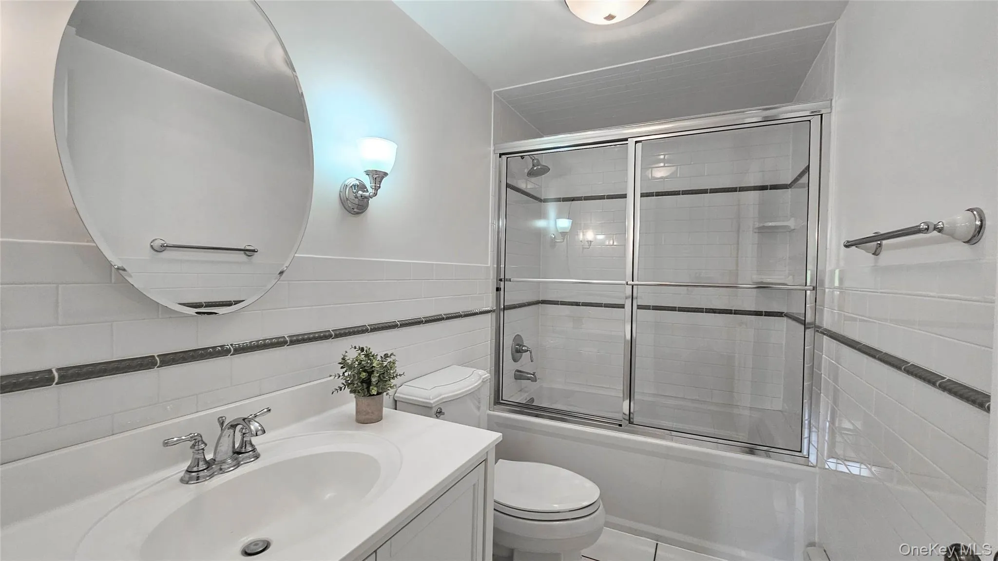 Bathroom with tile walls, vanity, and bath shower combo with glass doors. Bathroom with tile walls, vanity, and bath shower combo with glass doors.