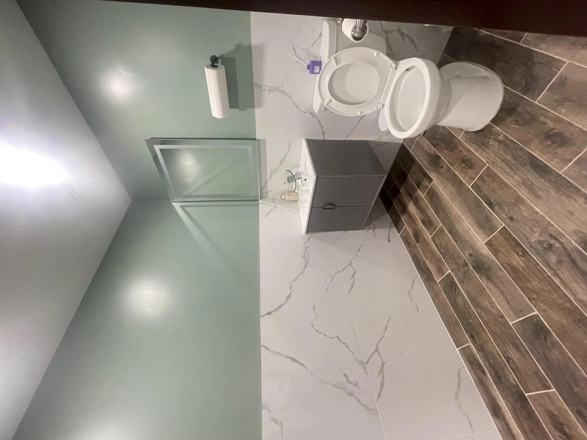 Bathroom with tile walls, vanity, wood finish floors, and a wainscoted wall Bathroom with tile walls, vanity, wood finish floors, and a wainscoted wall