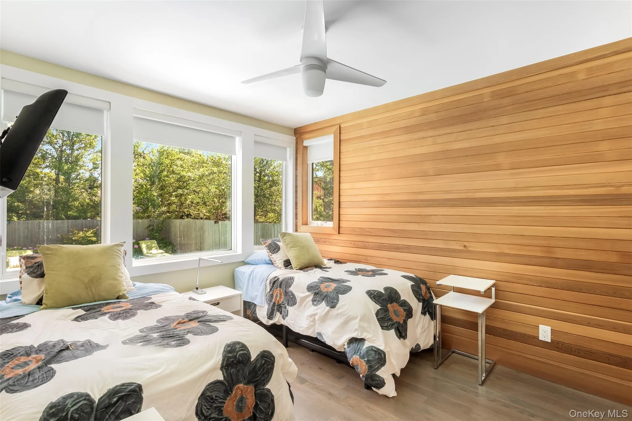 Bedroom featuring wooden walls, wood finished floors, and ceiling fan Bedroom featuring wooden walls, wood finished floors, and ceiling fan