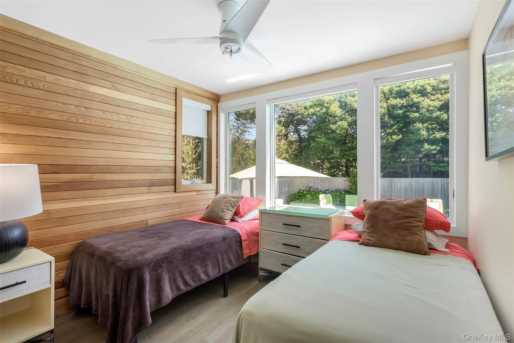 Bedroom with wooden walls, ceiling fan, and wood finished floors Bedroom with wooden walls, ceiling fan, and wood finished floors