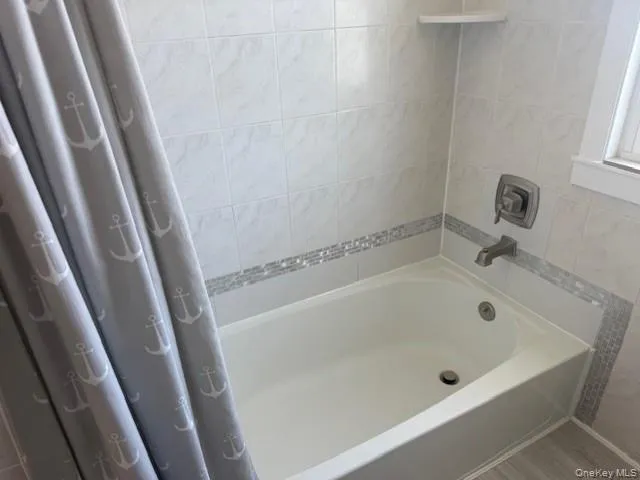 Bathroom featuring tile walls and shower / bath combination with curtain Bathroom featuring tile walls and shower / bath combination with curtain