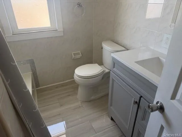 Full bath featuring tile walls and vanity Full bath featuring tile walls and vanity