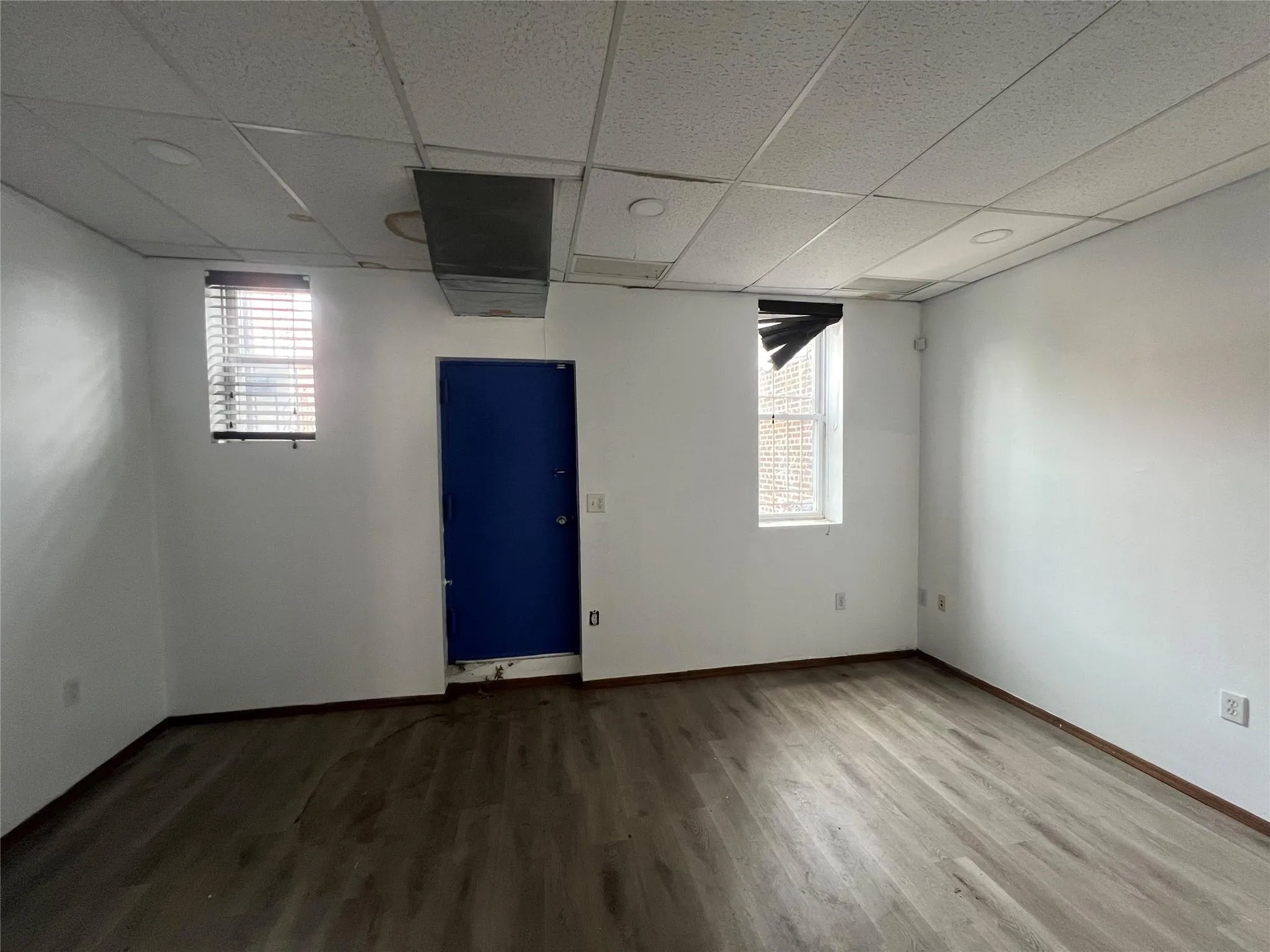 Spare room featuring a drop ceiling, plenty of natural light, and wood finished floors Spare room featuring a drop ceiling, plenty of natural light, and wood finished floors