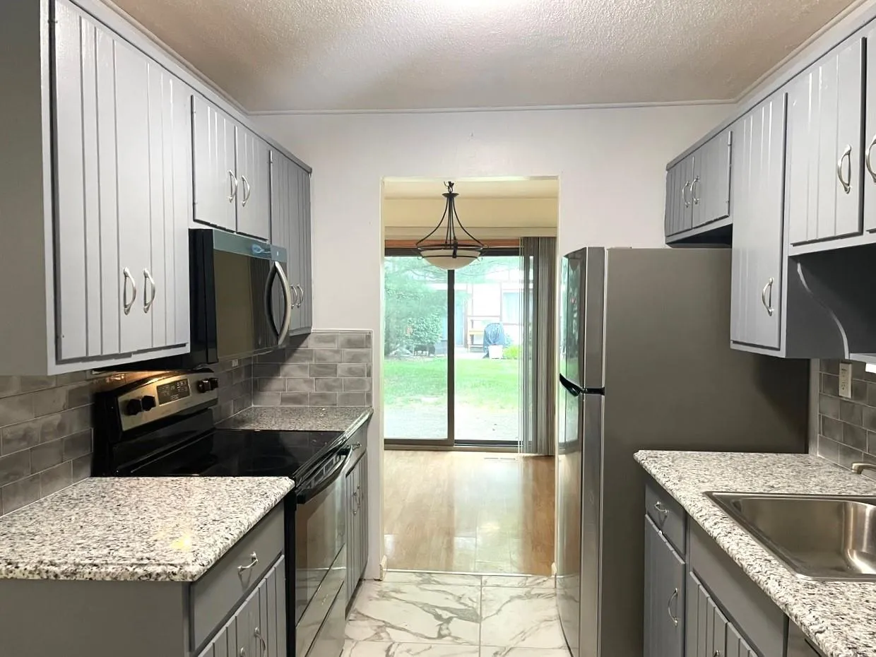 Kitchen with appliances with stainless steel finishes, gray cabinets, light marble finish flooring, backsplash, and a textured ceiling Kitchen with appliances with stainless steel finishes, gray cabinets, light marble finish flooring, backsplash, and a textured ceiling