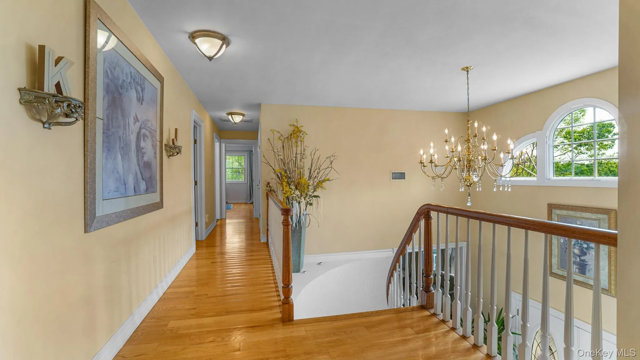 Hall featuring wood finished floors, a chandelier, and an upstairs landing Hall featuring wood finished floors, a chandelier, and an upstairs landing