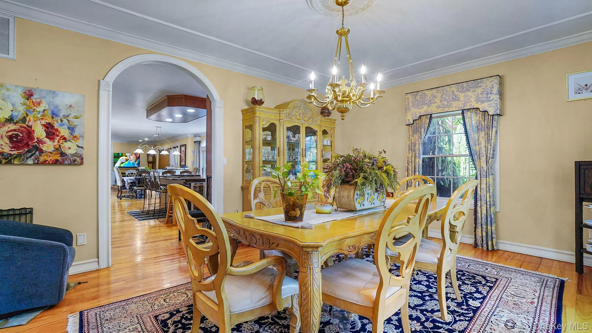 Dining space featuring a chandelier, wood finished floors, arched walkways, and ornamental molding Dining space featuring a chandelier, wood finished floors, arched walkways, and ornamental molding