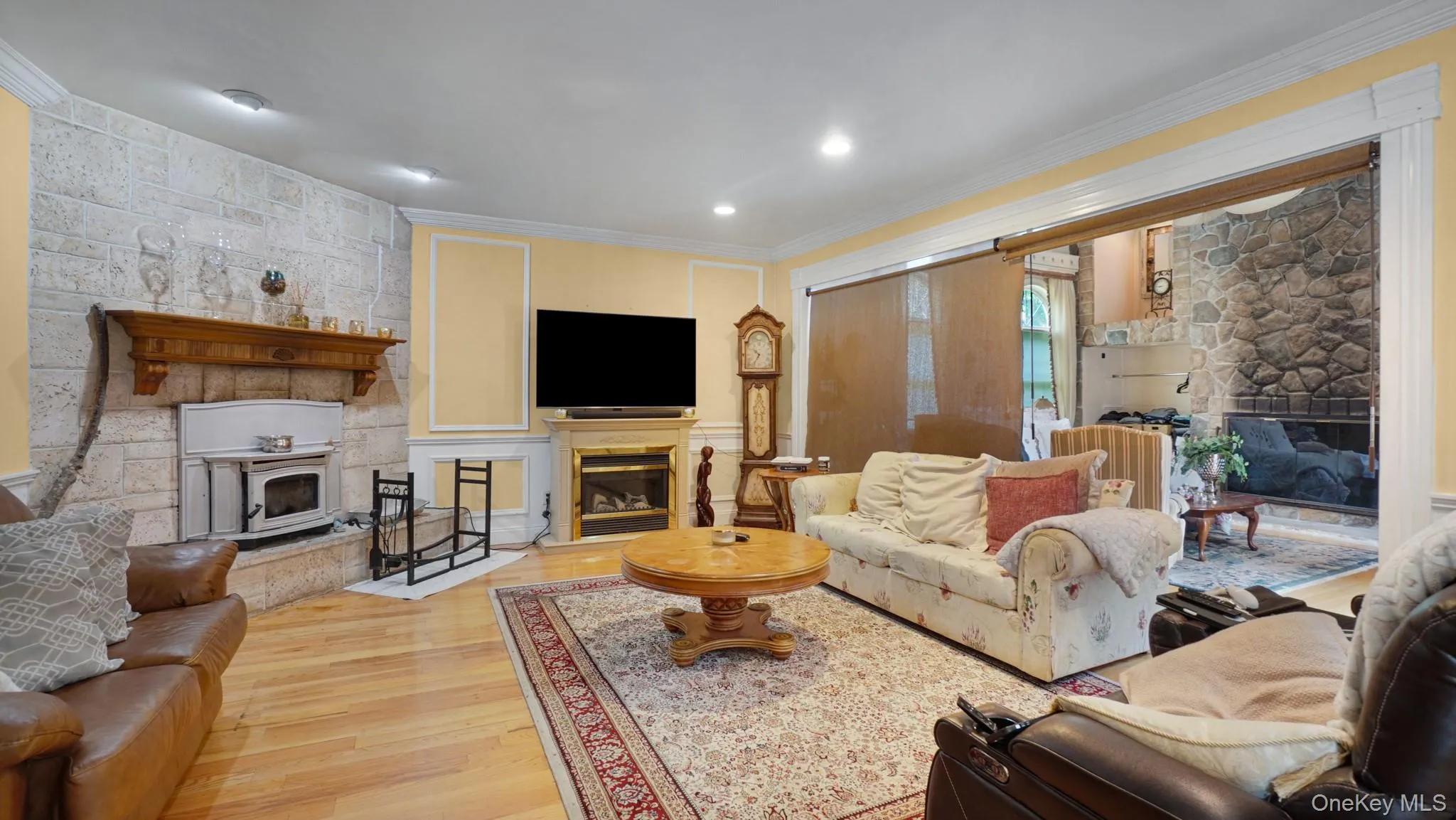 Living room featuring a glass covered fireplace, wood finished floors, crown molding, and recessed lighting Living room featuring a glass covered fireplace, wood finished floors, crown molding, and recessed lighting