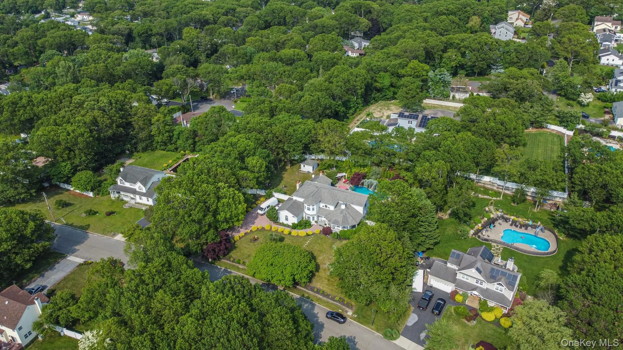 Aerial view of property's location with a heavily wooded area and a pool Aerial view of property's location with a heavily wooded area and a pool