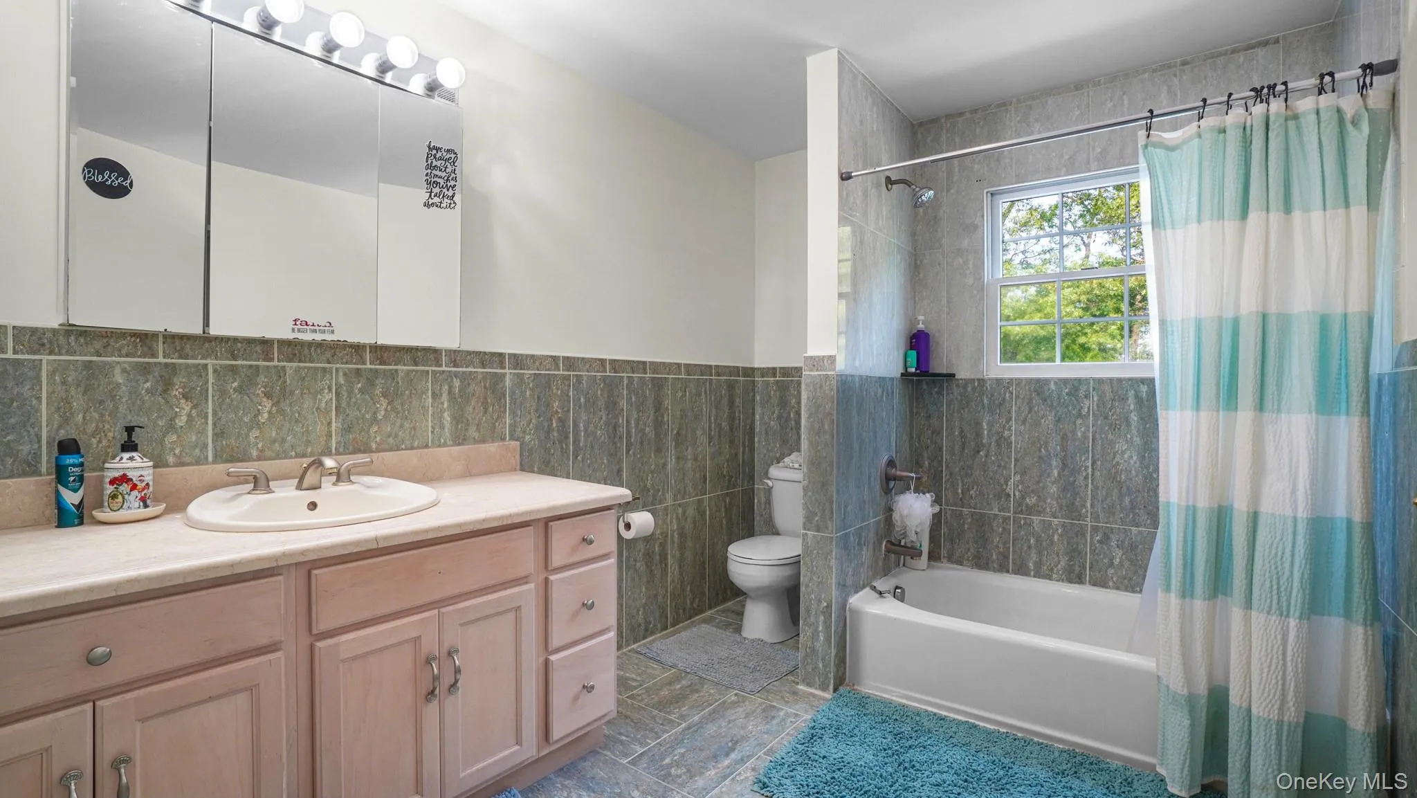 Full bathroom with shower / bathtub combination with curtain, vanity, and tile walls Full bathroom with shower / bathtub combination with curtain, vanity, and tile walls