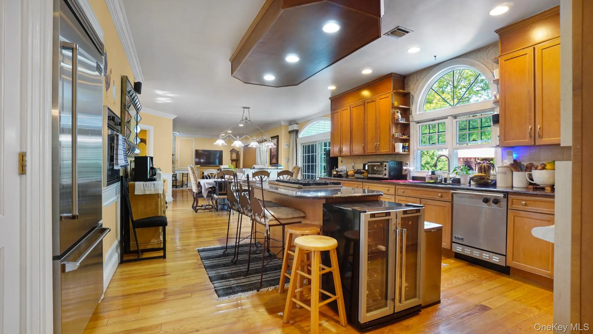 Kitchen featuring stainless steel appliances, open shelves, ornamental molding, a center island, and a kitchen bar Kitchen featuring stainless steel appliances, open shelves, ornamental molding, a center island, and a kitchen bar