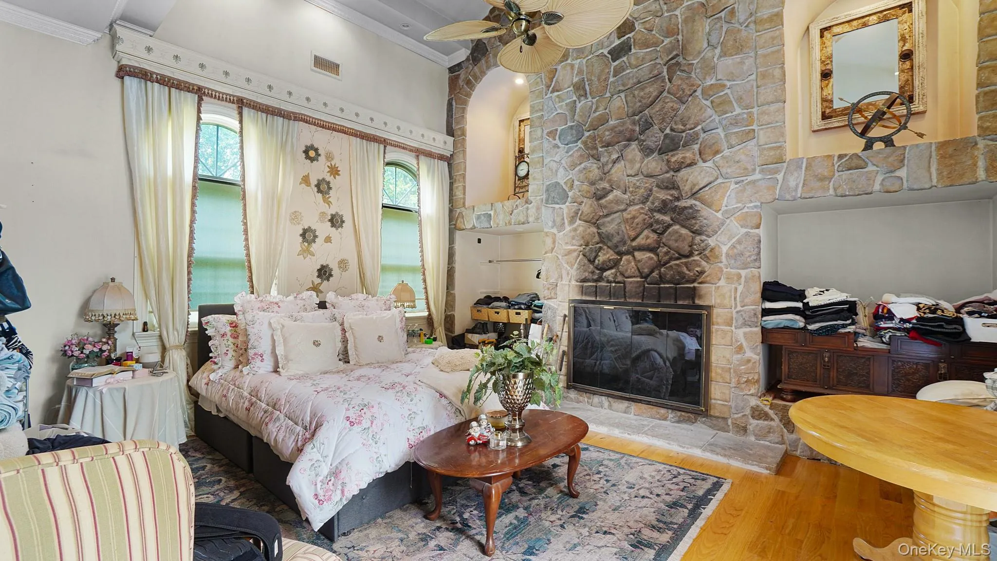 Bedroom with crown molding, wood finished floors, and a fireplace Bedroom with crown molding, wood finished floors, and a fireplace
