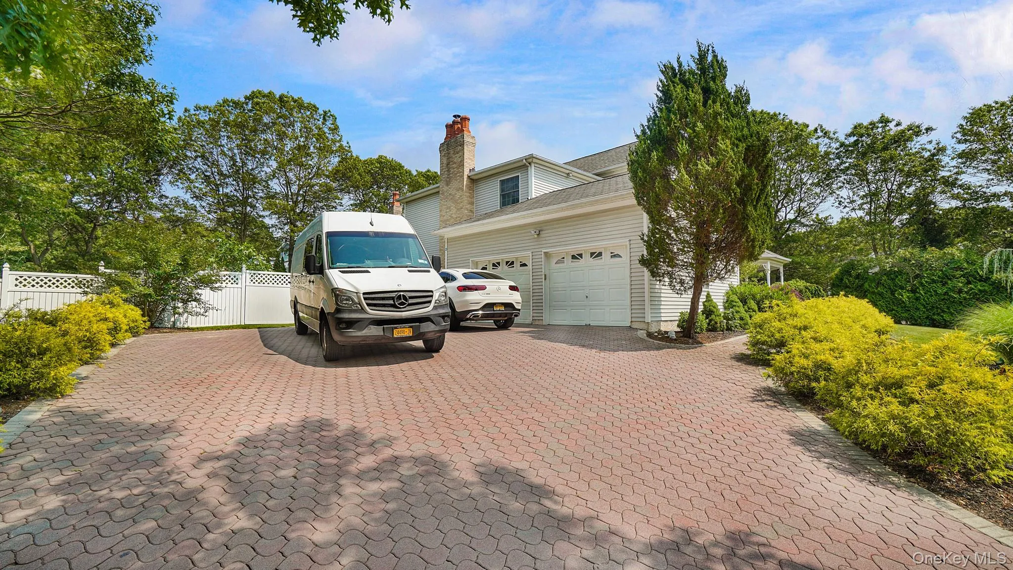 View of side of home featuring an attached garage, decorative driveway, and a chimney View of side of home featuring an attached garage, decorative driveway, and a chimney