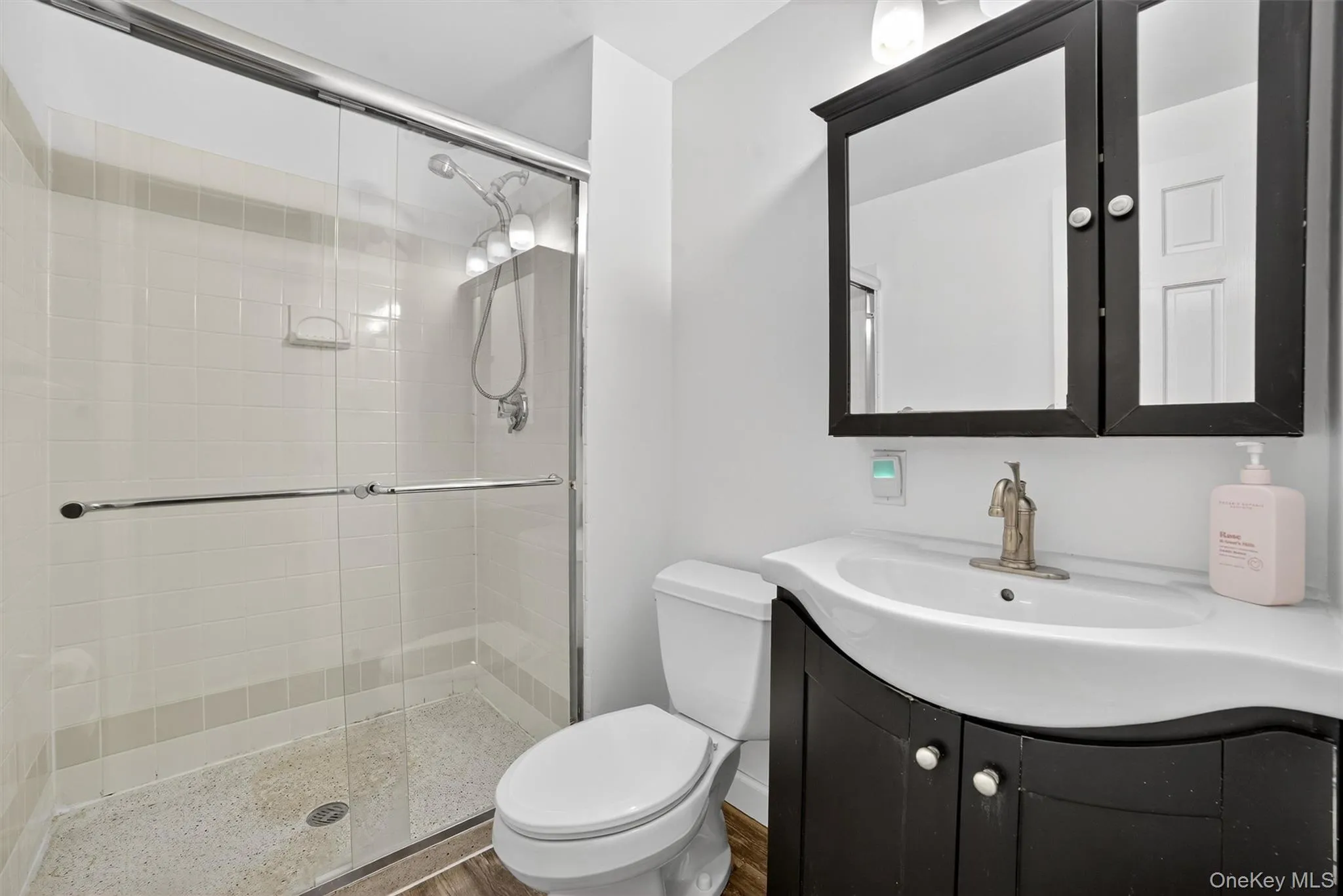 Full bathroom featuring a shower stall, vanity, and wood finished floors Full bathroom featuring a shower stall, vanity, and wood finished floors