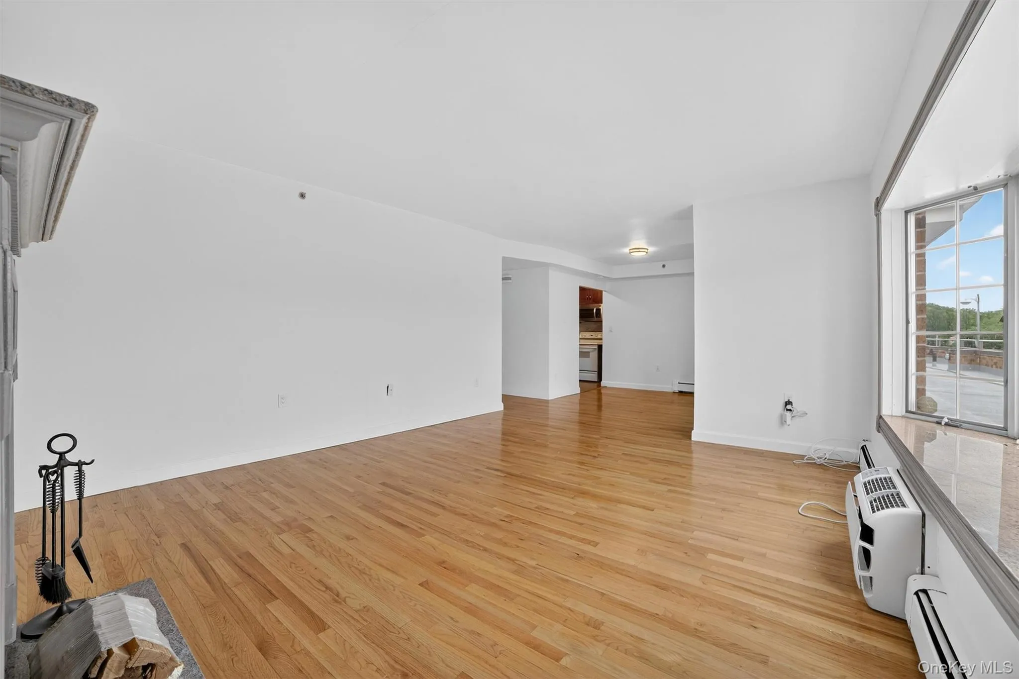 Unfurnished living room with baseboard heating and light wood finished floors Unfurnished living room with baseboard heating and light wood finished floors
