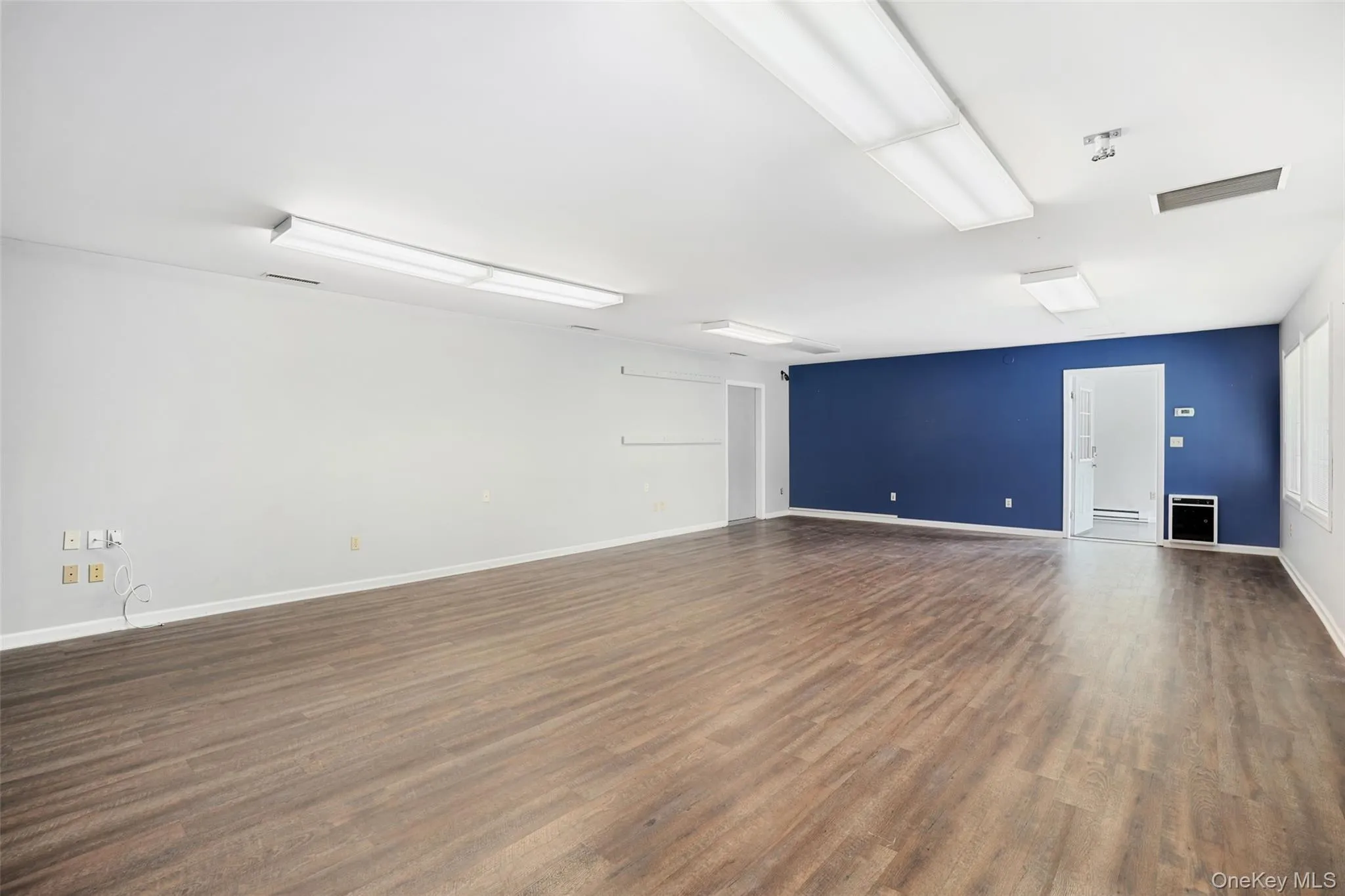 Unfurnished room with dark wood-style flooring and baseboards Unfurnished room with dark wood-style flooring and baseboards