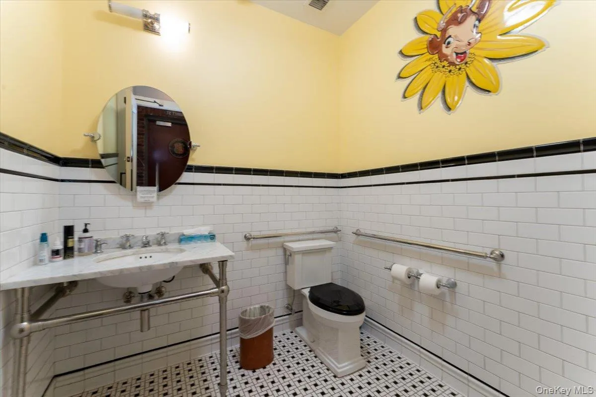 Bathroom featuring a wainscoted wall, tile patterned flooring, and tile walls Bathroom featuring a wainscoted wall, tile patterned flooring, and tile walls