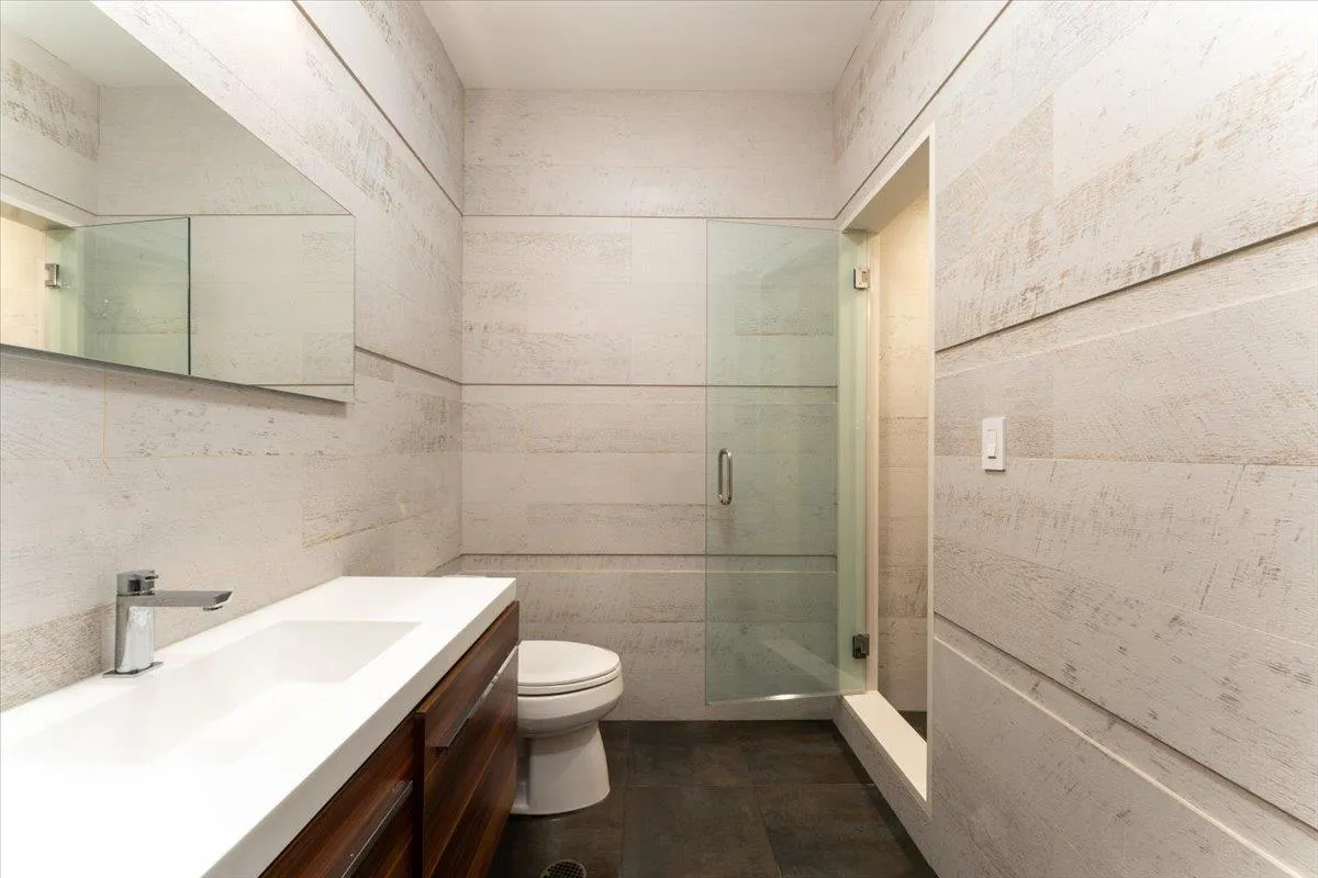 Bathroom featuring tile walls, vanity, and a shower stall Bathroom featuring tile walls, vanity, and a shower stall