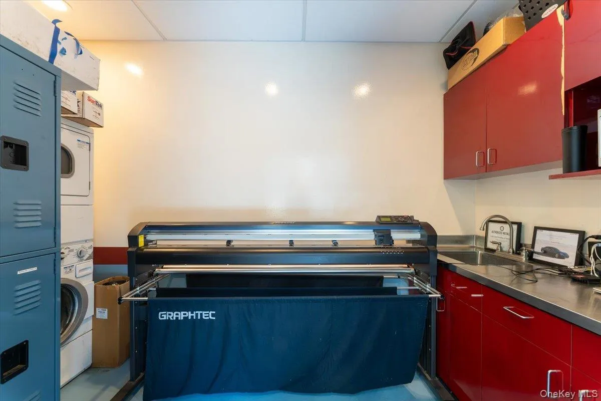 Kitchen with red cabinetry, stacked washing machine and dryer, and stainless steel countertops Kitchen with red cabinetry, stacked washing machine and dryer, and stainless steel countertops