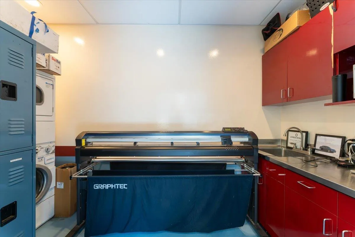 Kitchen with red cabinetry, stacked washing machine and dryer, and stainless steel countertops Kitchen with red cabinetry, stacked washing machine and dryer, and stainless steel countertops