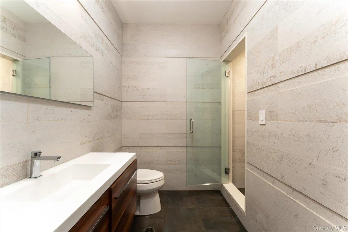 Bathroom featuring tile walls, vanity, and a shower stall Bathroom featuring tile walls, vanity, and a shower stall