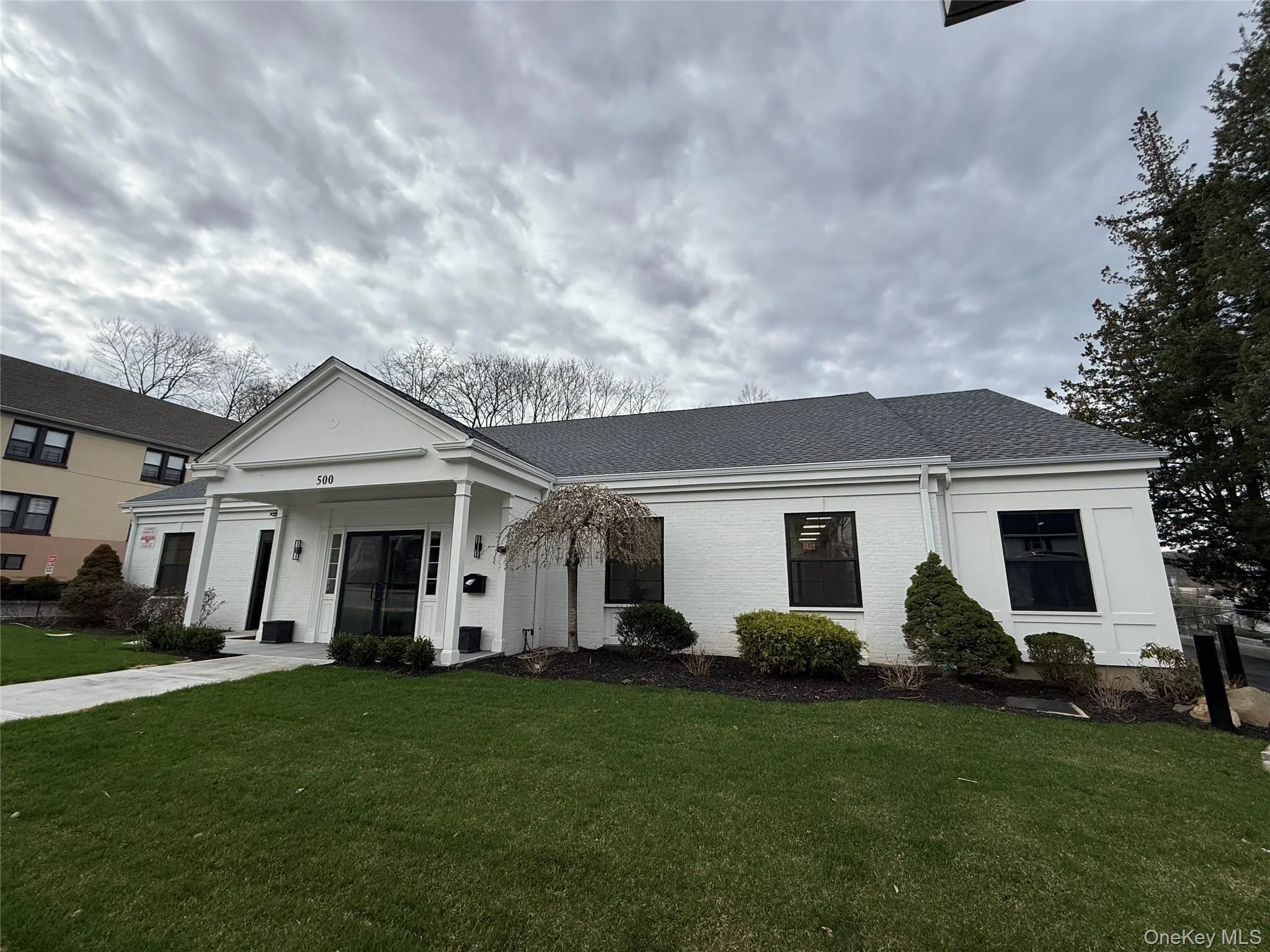 Neoclassical home with a front yard, roof with shingles, and brick siding Neoclassical home with a front yard, roof with shingles, and brick siding