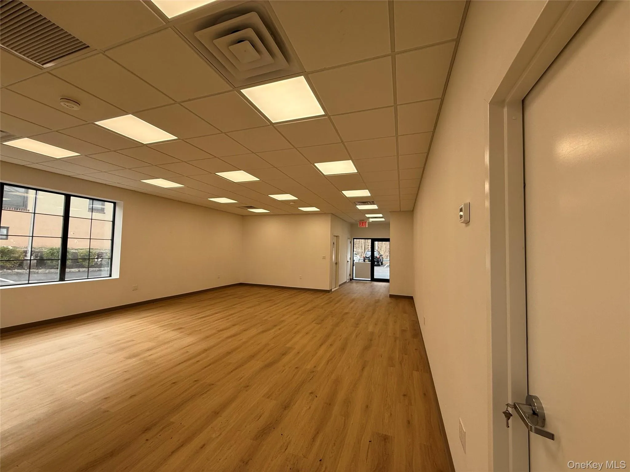 Empty room featuring light wood-style flooring, a smoke detector, and a paneled ceiling Empty room featuring light wood-style flooring, a smoke detector, and a paneled ceiling