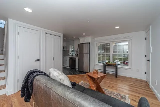 Living room featuring light wood finished floors, recessed lighting, stairs, and baseboard heating Living room featuring light wood finished floors, recessed lighting, stairs, and baseboard heating