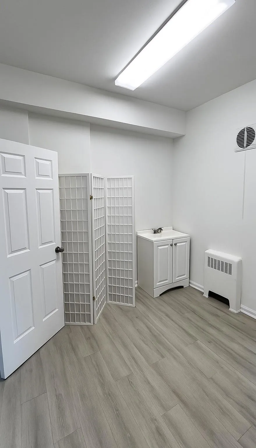 Below grade area featuring radiator heating unit and light wood-style floors Below grade area featuring radiator heating unit and light wood-style floors