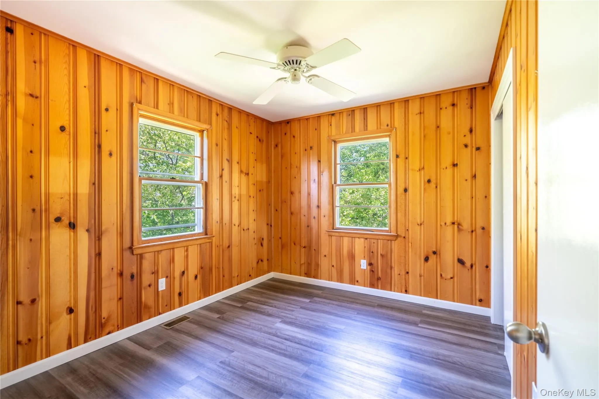 Empty room featuring wood finished floors, a ceiling fan, and wood walls Empty room featuring wood finished floors, a ceiling fan, and wood walls