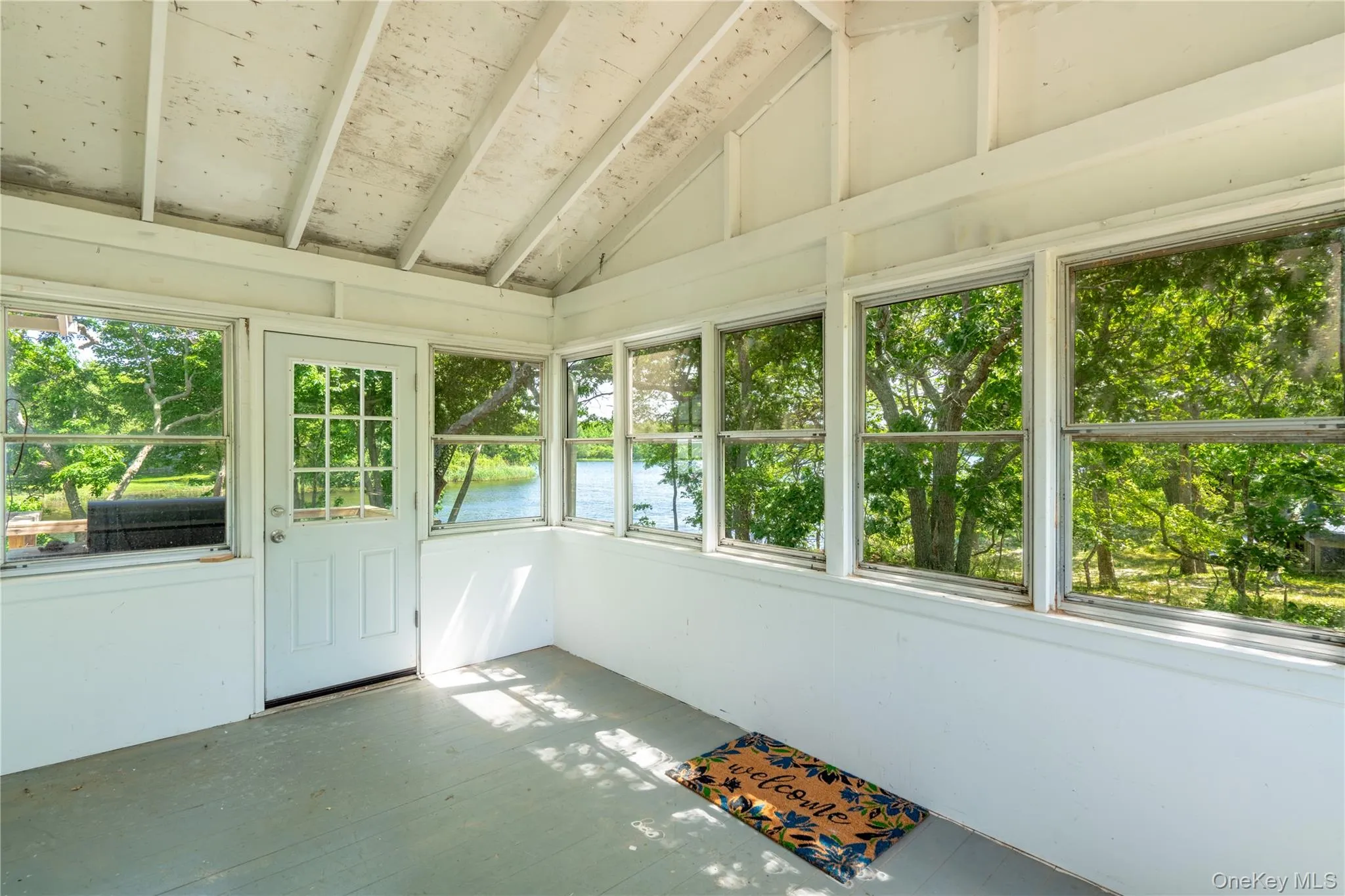 Unfurnished sunroom with a water view and lofted ceiling Unfurnished sunroom with a water view and lofted ceiling