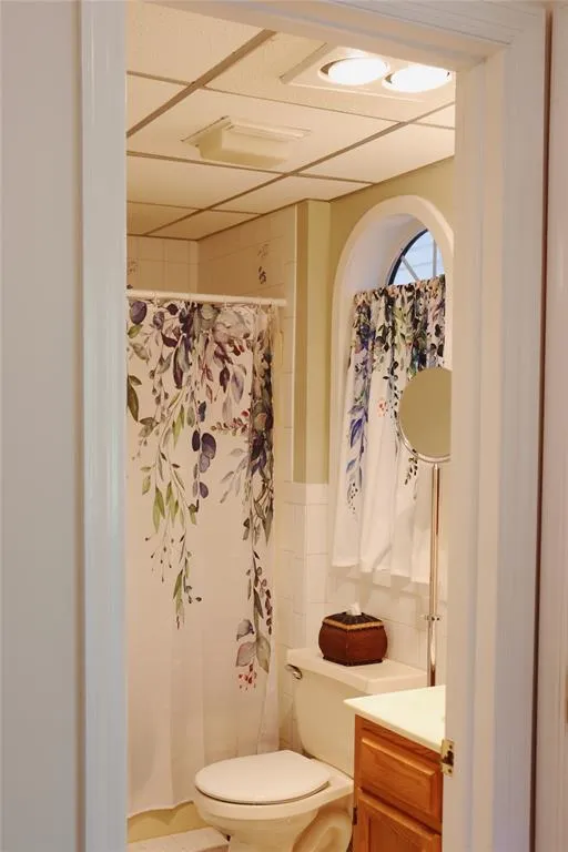 Full bath featuring tile walls, a shower with curtain, and vanity Full bath featuring tile walls, a shower with curtain, and vanity