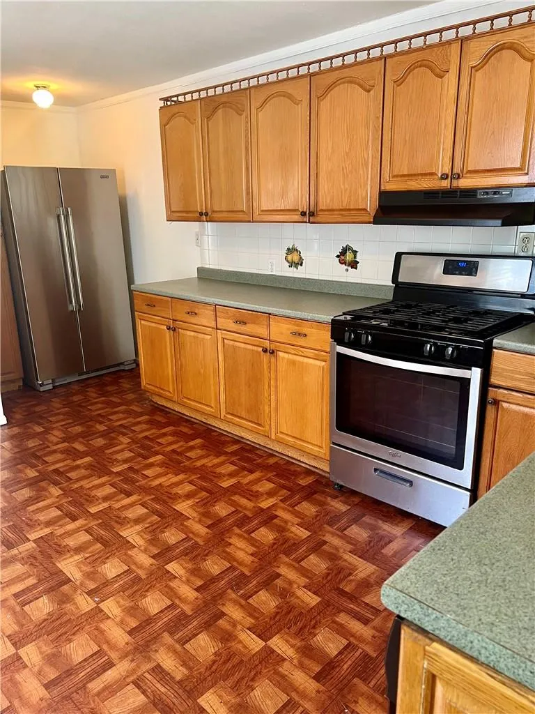 Kitchen with  parquet floors, tasteful backsplash, and appliances with stainless steel finishes Kitchen with  parquet floors, tasteful backsplash, and appliances with stainless steel finishes