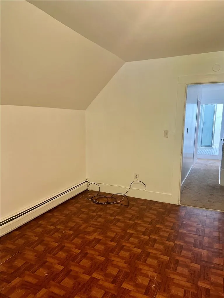 Bedroom featuring  a baseboard radiator, and lofted ceiling Bedroom featuring  a baseboard radiator, and lofted ceiling