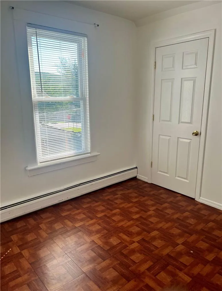 Bedroom featuring dark parquet floors and a baseboard radiator Bedroom featuring dark parquet floors and a baseboard radiator